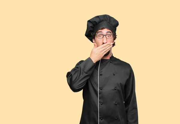 young crazy man as a chef Covering mouth with hand with a gesture of surprise, in order to remain silent and keep a secret.