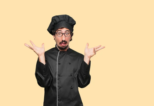 young crazy man as a chef shouting with a crazy, amazed look of surprise, holding head with both hands.