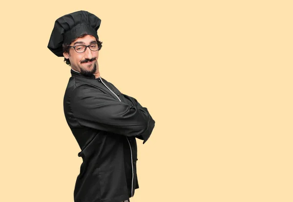 young crazy man as a chef with a proud, happy and confident expression; accepting a challenge with arms crossed, smiling and sure of success, giving an \