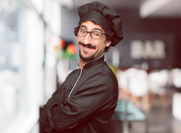 young crazy man as a chef standing sideways, with a proud, satisfied and happy look on face, smiling with arms crossed. Side or lateral view.