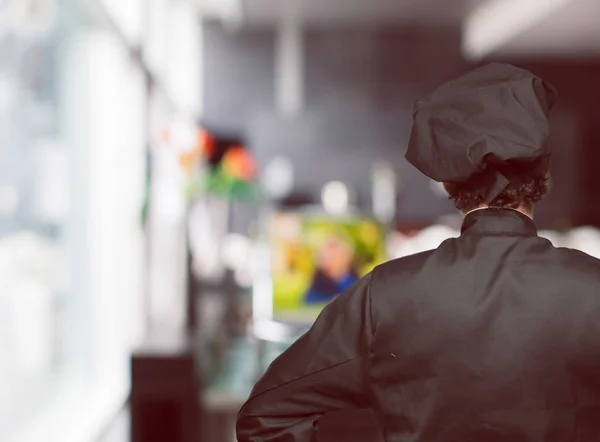 young crazy man as a chef with a proud, satisfied and happy look, with both hands on hips, as if confidently facing a challenge. Akimbo arms pose with a broad smile. May have an angry expression. Back or rear view.