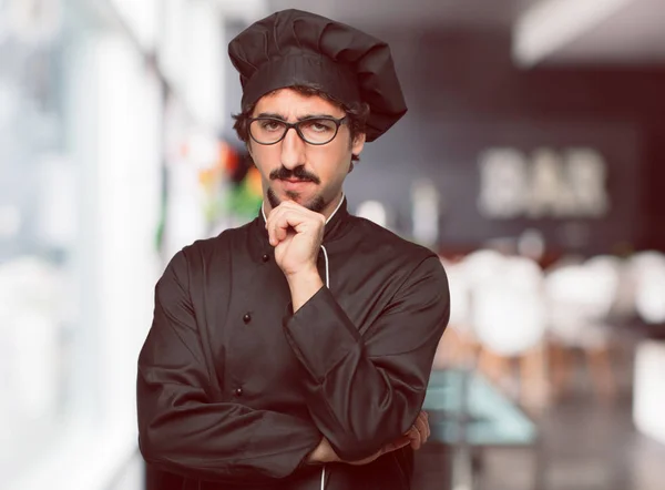 young crazy man as a chef With a confused and thoughtful look, looking sideways, thinking and wondering between different options.