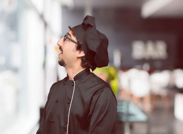 young crazy man as a chef smiling and looking up and sideways, towards the sky or to the spot where the publicist may place a concept or message.