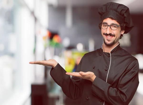 young crazy man as a chef smiling with a satisfied expression showing an object or concept with both hands.