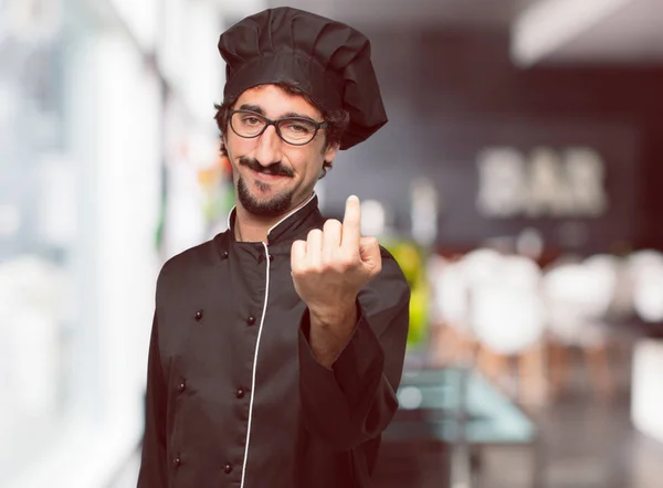 young crazy man as a chef smiling with a proud, satisfied and happy look, making a gesture as if accepting a challenge, confident of success.