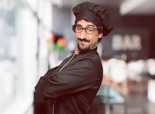 young crazy man as a chef with a proud, happy and confident expression; accepting a challenge with arms crossed, smiling and sure of success, giving an \