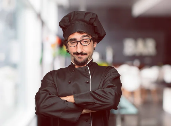 young crazy man as a chef with a proud, happy and confident expression; accepting a challenge with arms crossed, smiling and sure of success, giving an \