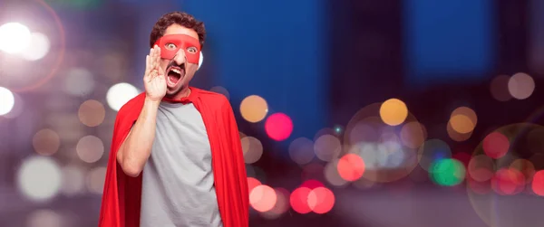 crazy man as a super hero shouting loud like crazy, calling with hand with an angry expression, communicating a big announcement.