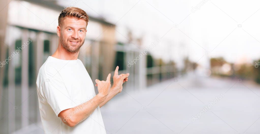 young blonde man smiling and pointing upwards with both hands, towards the place where the publicist may show a concept.