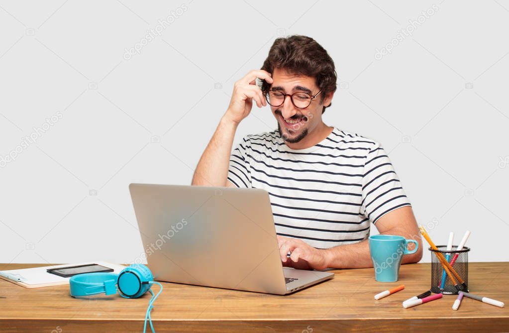 young bearded graphic designer with a laptop happily realizing some good and surprising news or having a great idea, smiling with an amazed expression while scratching head with hand.