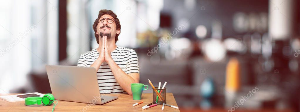 young bearded graphic designer with a laptop praying in a saintly manner, begging 
