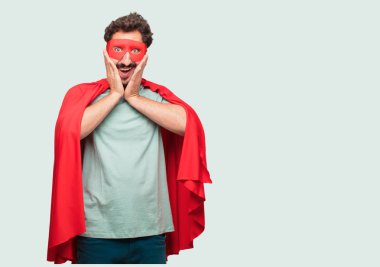 deli adam mutlu bir sürpriz ifade ile bir süper kahraman olarak gözleri geniş açık ve geniş gülümseme, iki eliyle tutarak yüz.