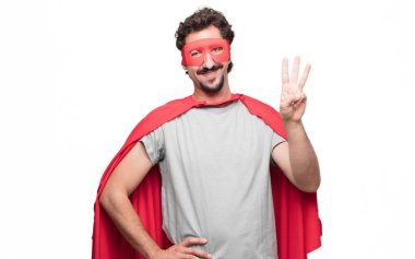 Genç gülümseyen ve görünümlü memnun ve mutlu, süper kahraman üç parmaklı sayılması sakallı.