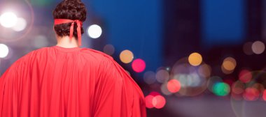 Genç süper kahraman arkadan görünüm, iki elini akimbo poz ile kalça üzerinde muhtemelen gurur ve tatmin hissi sakallı.