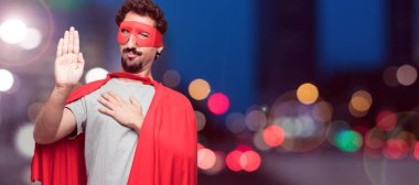 Genç süper kahraman güvenle gülümseyen bir samimi söz ver yoksa yemin, yaparken tek eliyle kalp üzerinde ciddiyetle küfür sakallı.