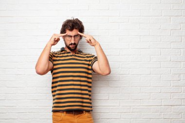 Concentrating sert bir fikirle ciddi bir göz alnına işaret her iki işaret parmakları ile düşünüyor genç aptal adam.