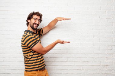 bir nesne veya her iki el arasında yanal düzenlenen kavramı gösterilen memnun bir ifadeyle gülümseyen genç aptal adam.