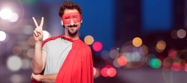 Young bearded super hero with a proud, happy and confident expression; smiling and showing off success while gesturing victory, giving an \