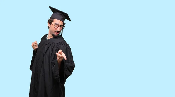 young graduated man smiling and dancing to fun, lively disco music, looking happy and in a joyful party mood.