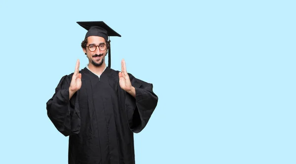 Jeune Homme Diplômé Souriant Avec Une Expression Satisfaite Montrant Objet — Photo