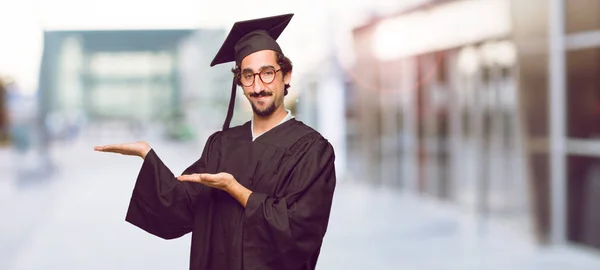 Junger Mann Mit Hochschulabschluss Lächelt Mit Zufriedenem Gesichtsausdruck Und Zeigt — Stockfoto