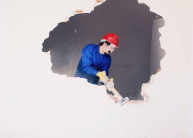 Kırmızı koruma kask ve mavi bir kazan takım elbise giyen genç bir işçi. Yıkım kavramı.