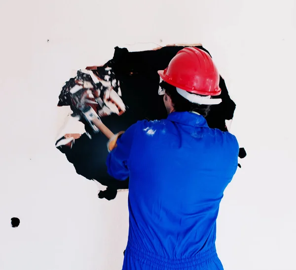 Young worker with a red protection helmet and wearing a blue boiler suit. Demolition concept.