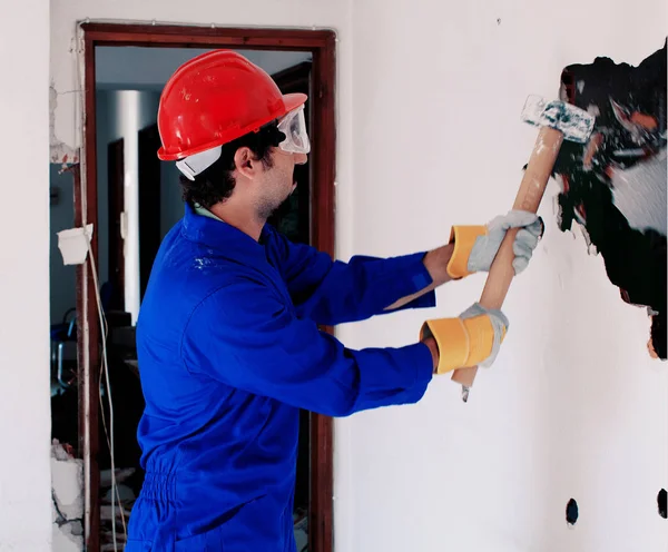 Young worker with a red protection helmet and wearing a blue boiler suit. Demolition concept.