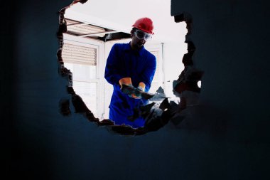 Kırmızı koruma kask ve mavi bir kazan takım elbise giyen genç bir işçi. Yıkım kavramı.