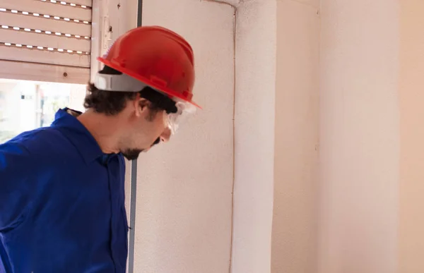 Young worker with a red protection helmet and wearing a blue boiler suit. Demolition concept.