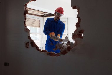 Kırmızı koruma kask ve mavi bir kazan takım elbise giyen genç bir işçi. Yıkım kavramı.