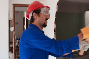 Kırmızı koruma kask ve mavi bir kazan takım elbise giyen genç bir işçi. Yıkım kavramı.