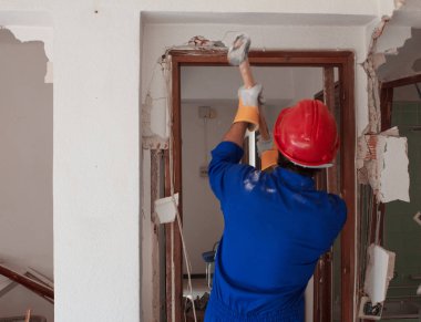 Kırmızı koruma kask ve mavi bir kazan takım elbise giyen genç bir işçi. Yıkım kavramı.