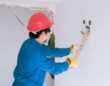 Kırmızı koruma kask ve mavi bir kazan takım elbise giyen genç bir işçi. Yıkım kavramı.