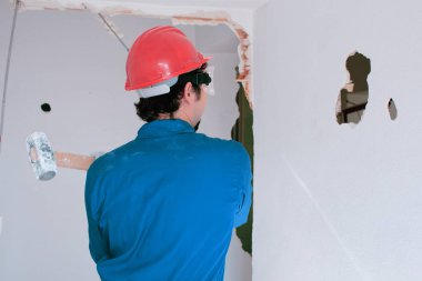 Kırmızı koruma kask ve mavi bir kazan takım elbise giyen genç bir işçi. Yıkım kavramı.