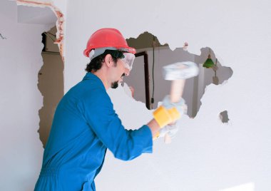 Kırmızı koruma kask ve mavi bir kazan takım elbise giyen genç bir işçi. Yıkım kavramı.