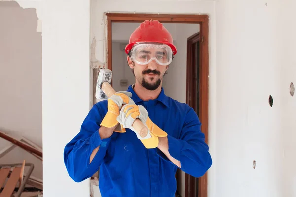 Young worker with a red protection helmet and wearing a blue boiler suit. Demolition concept.