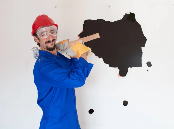 Young worker with a red protection helmet and wearing a blue boiler suit. Demolition concept.