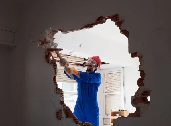 Young worker with a red protection helmet and wearing a blue boiler suit. Demolition concept.