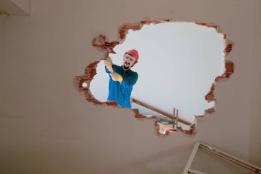 Kırmızı koruma kask ve mavi bir kazan takım elbise giyen genç bir işçi. Yıkım kavramı.