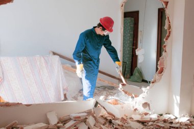 Kırmızı koruma kask ve mavi bir kazan takım elbise giyen genç bir işçi. Yıkım kavramı.