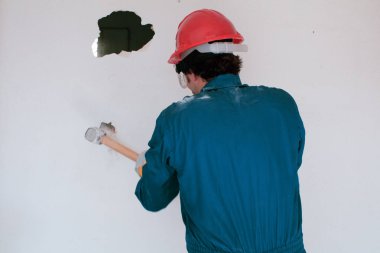 Kırmızı koruma kask ve mavi bir kazan takım elbise giyen genç bir işçi. Yıkım kavramı.