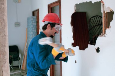 Kırmızı koruma kask ve mavi bir kazan takım elbise giyen genç bir işçi. Yıkım kavramı.
