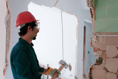 Kırmızı koruma kask ve mavi bir kazan takım elbise giyen genç bir işçi. Yıkım kavramı.