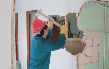 Kırmızı koruma kask ve mavi bir kazan takım elbise giyen genç bir işçi. Yıkım kavramı.