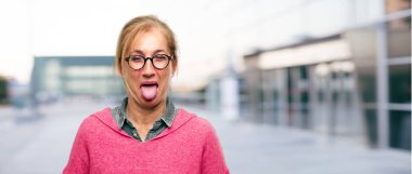 Şaka, komik, aptalca ve oynak bir ifadeyle dil yapışkanlık dışarı, bir aptal gibi arıyorum güzel yetişkin sarışın kadın.