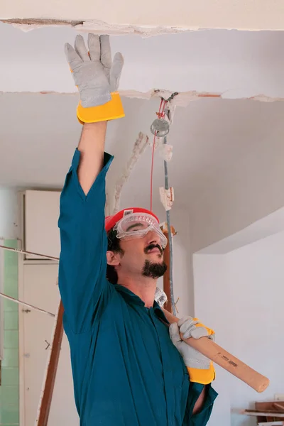 Young worker with a red protection helmet and wearing a blue boiler suit. Demolition concept.