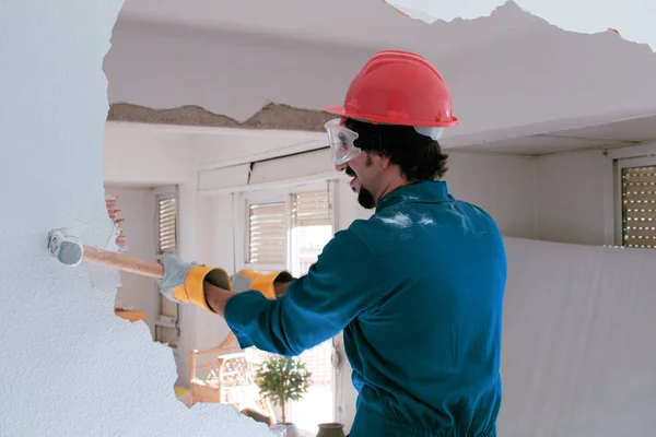 Young worker with a red protection helmet and wearing a blue boiler suit. Demolition concept.