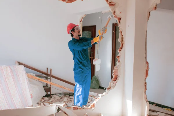 Young worker with a red protection helmet and wearing a blue boiler suit. Demolition concept.