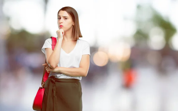 young pretty woman With a confused and thoughtful look, looking sideways, thinking and wondering between different options.